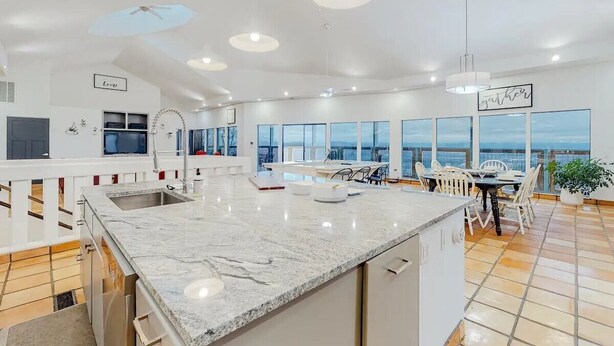Una cocina moderna con una isla grande, un comedor con vistas y un balcón con mesa y sillas.