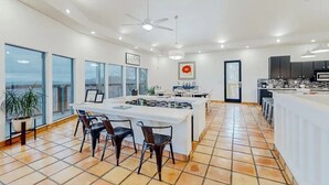 Una cocina moderna con una isla central, ventanas amplias y un comedor con sillas.