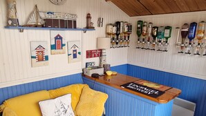 Zona de bar con mostrador azul, sofá amarillo y decoración temática náutica.