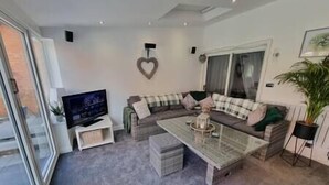 Una sala de estar moderna con un sofá modular, una mesa de centro de vidrio y un televisor de pantalla plana.