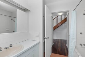 A bathroom with a white sink, mirror, and shower.