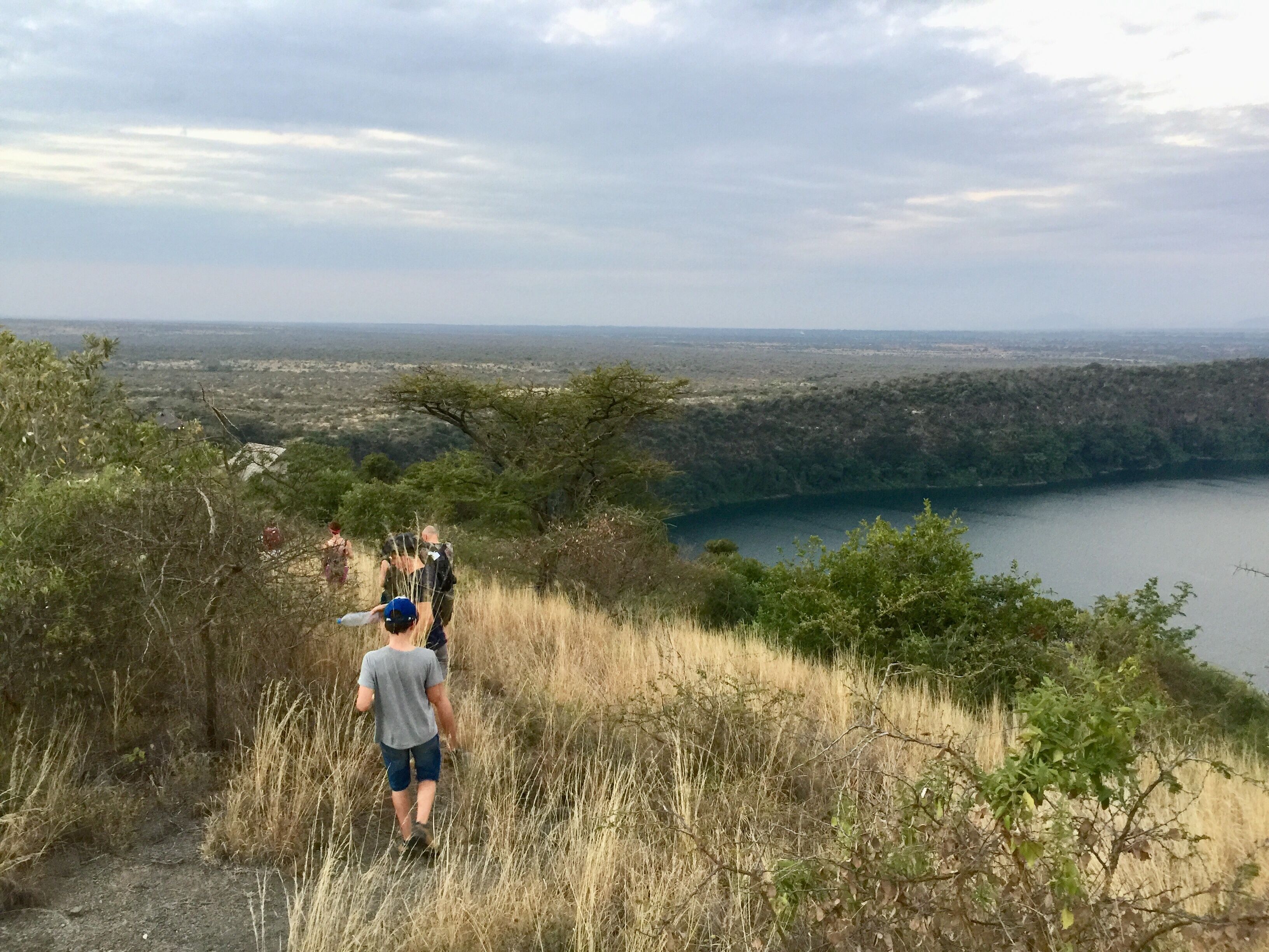 Un sentier de randonnée offrant une vue sur un lac et sur la silhouette d'une ville au loin.