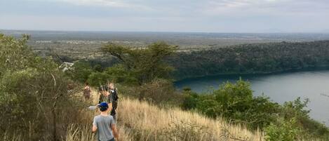 Un sentier de randonnée offrant une vue sur un lac et sur la silhouette d'une ville au loin.