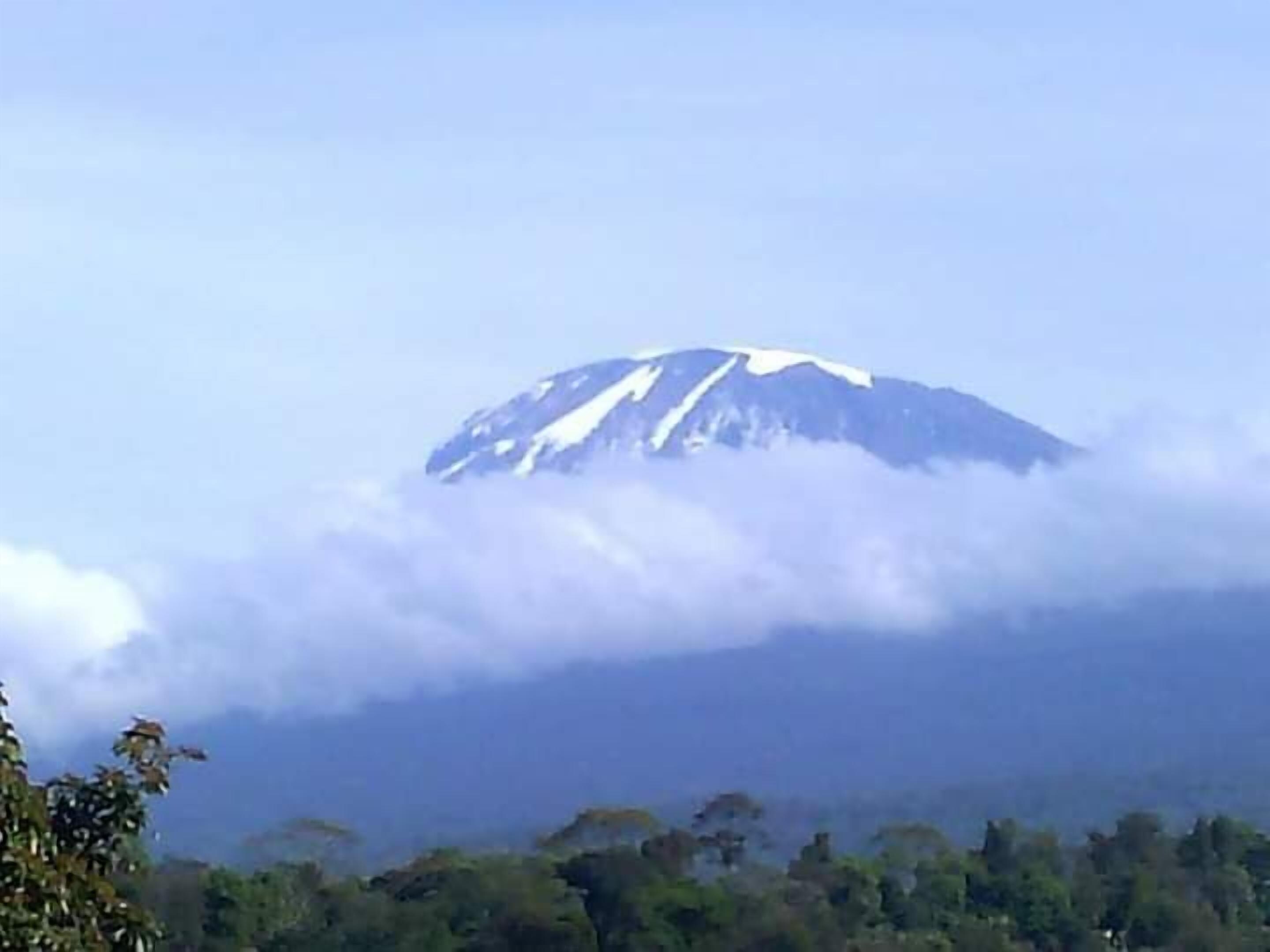 Montanha com pico nevado parcialmente coberto por nuvens.