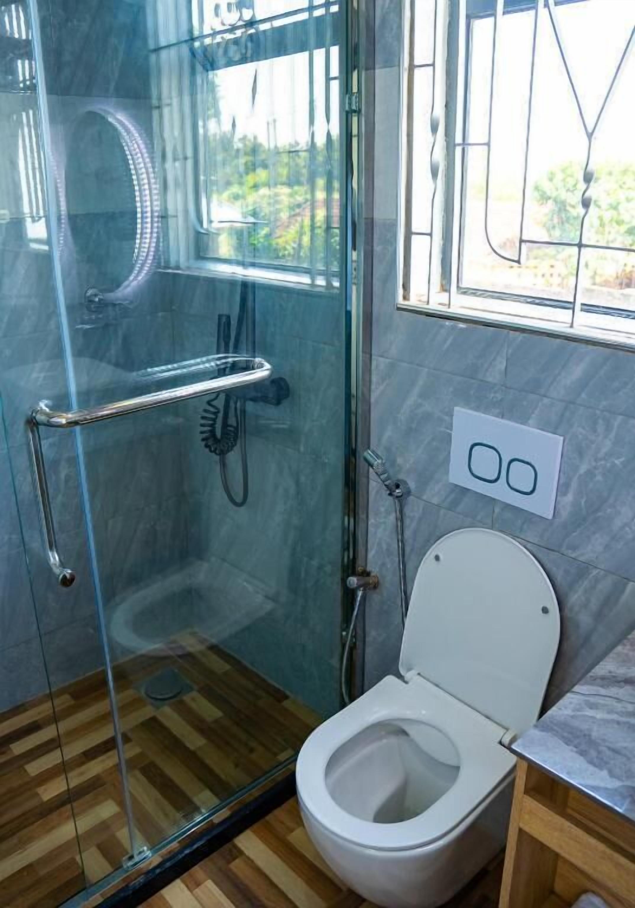 A modern bathroom with a glass-enclosed shower, a white toilet, and a marble-tiled wall.