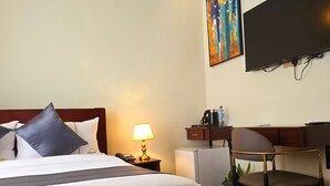 Une chambre d’hôtel équipée d’un lit, d’un bureau, d’une chaise, d’une télévision et d’un appareil de climatisation.