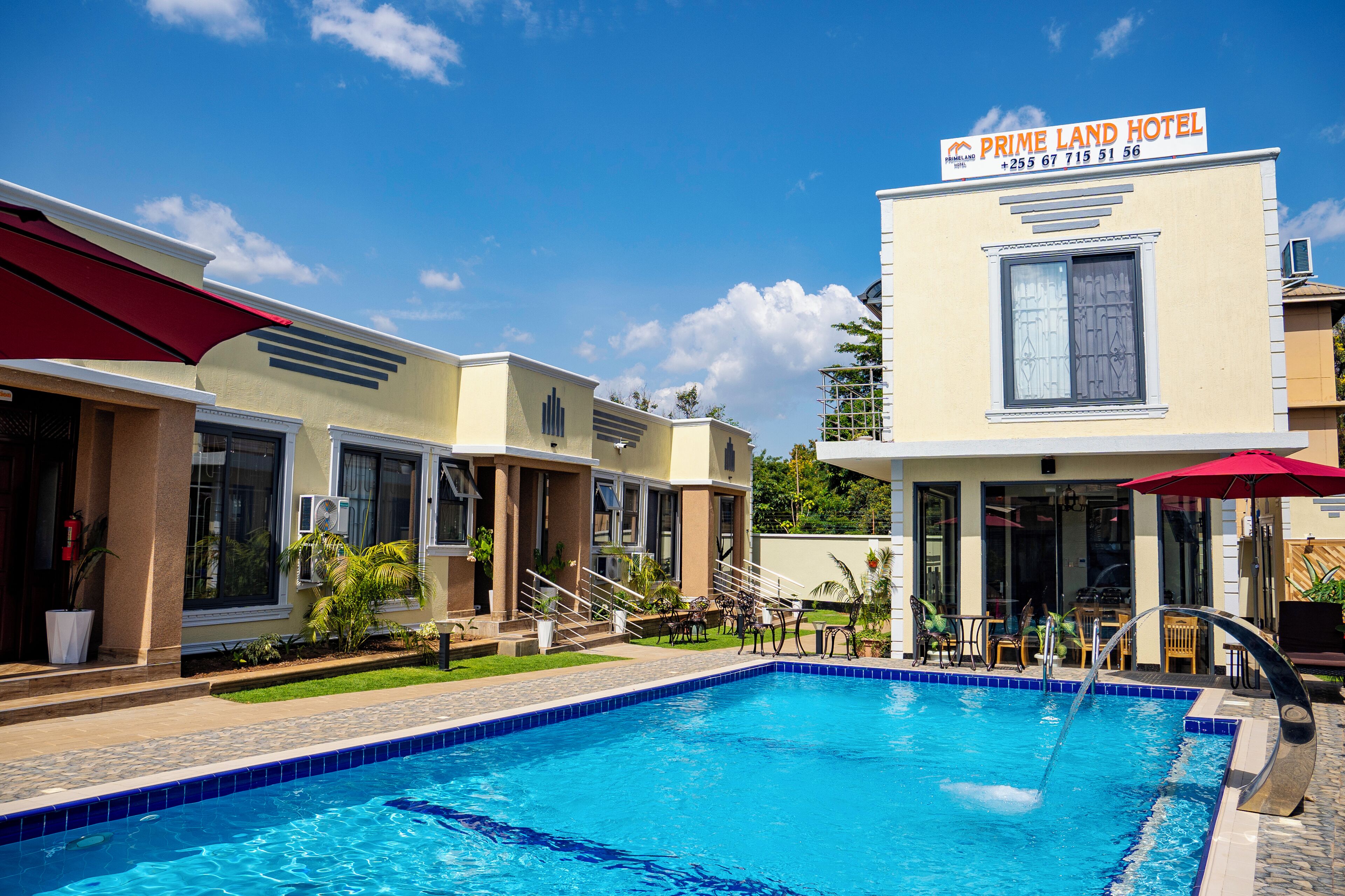 A hotel with a swimming pool, outdoor seating, and a sign indicating it is the Prime Land Hotel.
