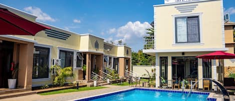 Un hôtel doté d’une piscine, d’un espace extérieur aménagé et d’une enseigne indiquant qu’il s’agit du Prime Land Hotel.