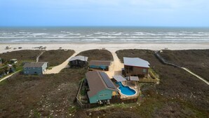 A coastal property with multiple houses, a swimming pool, and a beach view.