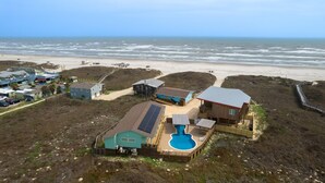 A beachfront property with a swimming pool, multiple buildings, and a beach view.
