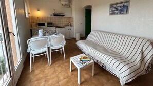 A compact living space with a kitchenette, a dining area with a table and chairs, and a striped sofa.