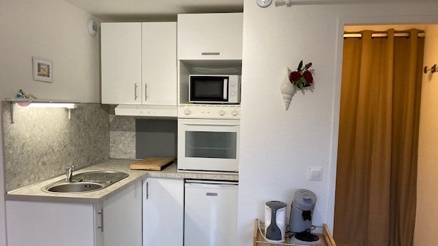A compact kitchen with a sink, microwave, oven, and a small refrigerator. - Charming 2-room apartment with balcony near the beach (Villers-sur-Mer)