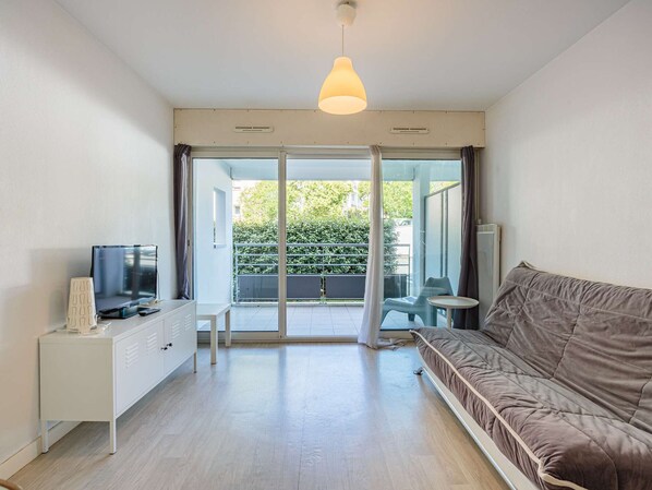 A modern living room with a sofa, a TV, a small table, and a cabinet.