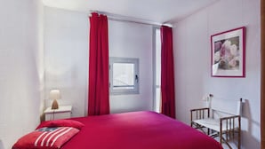 A bedroom with a bed, a chair, a window, and a picture on the wall. - 2-room apartment with terrace on beachfront for rent (Le Grau d'Agde)