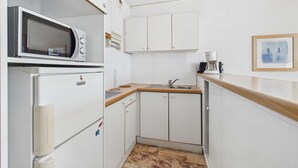 A compact kitchen with white cabinets, a microwave, a coffee maker, and a tiled backsplash. - 2-room apartment with terrace on beachfront for rent (Le Grau d'Agde)