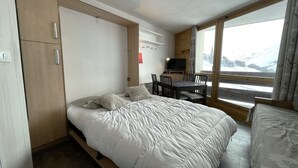 A bedroom with a bed, a desk, and a TV. - Cozy Studio for 3, Ski-in/Ski-out, Balcony, South Exposure, Preyerand, Les Menuires (Les Menuires)
