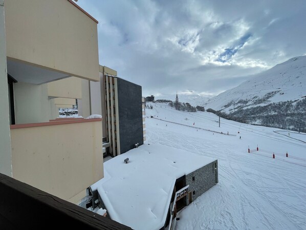 A snow-covered ski slope with a building adjacent to it.