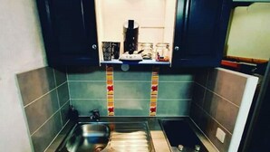 Uma cozinha compacta com pia, cafeteira e uma pequena prateleira com potes.