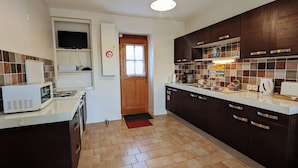 Uma cozinha moderna com armários de madeira escura, bancada branca e painel de azulejos.