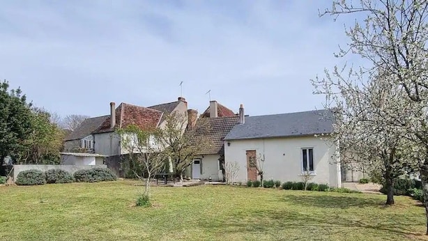 Um imóvel residencial com gramado na frente, um pequeno jardim e uma casa de dois andares com telhado inclinado.