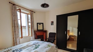 Quarto com cama, escrivaninha, cadeira, guarda-roupa e espelho.