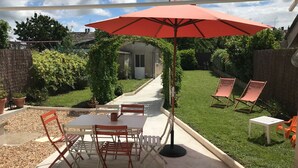 Een terras met een tafel, stoelen, een parasol en een gazon.