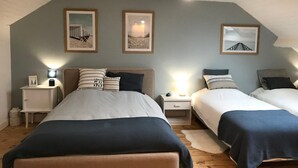 Een slaapkamer met twee bedden, een houten plafond en ingelijste foto’s aan de muur.