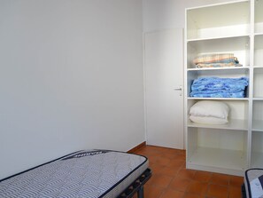Une pièce comprenant un lit, une armoire et un sol carrelé.
