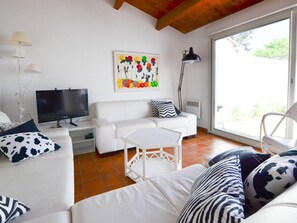 Un salon avec un canapé blanc, un téléviseur et un tableau accroché au mur.
