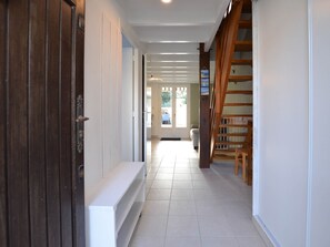 A hallway with a wooden door, a white bench, and a staircase. - House with terrace, near beach and shops (La Palmyre)