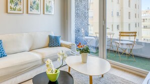 Un salon moderne avec un canapé, une table basse et un balcon équipé d’une table et de chaises.