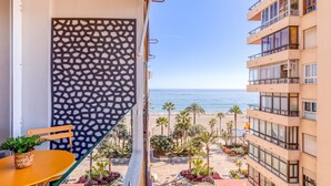 Un balcon donnant sur la plage, un mur orné d’un motif et une table avec une plante.