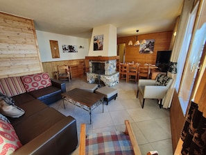 Una sala de estar acogedora con sofá, mesa de centro y chimenea. Hay un comedor con sillas de madera y una mesa.
