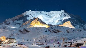 A snow-covered mountain with a ski lift and illuminated buildings in the foreground. - Cozy Apartment in Val Thorens - 4 pers - Balcony - Near Slopes (Val Thorens)