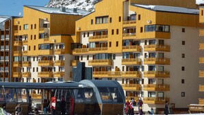 Un hotel a più piani con balconi e una funivia sullo sfondo.