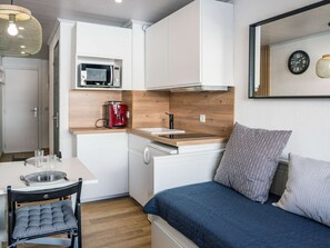 A compact kitchenette with a microwave, coffee machine, and a sink. There is a dining table with chairs and a bed with pillows. - Renovated 18m² Apartment, Val Thorens - 2 people, balcony, near slopes (Val Thorens)