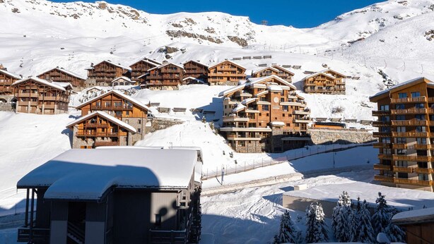 Una montagna innevata con chalet in legno e una seggiovia.