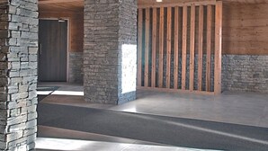 Un interior espacioso con pilares de piedra, vigas de madera e iluminación empotrada.