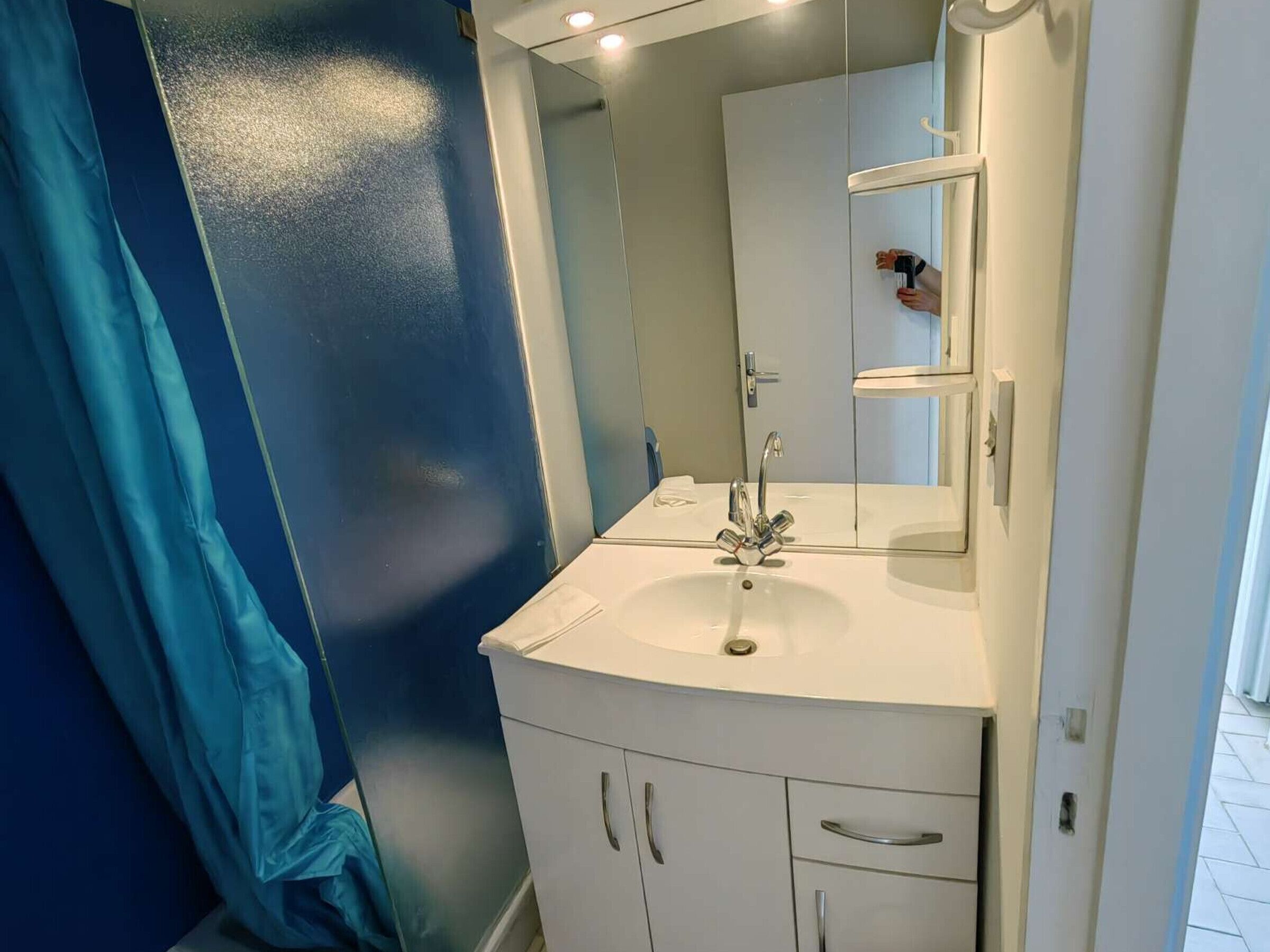 A bathroom with a white sink, a mirror, and a blue wall.