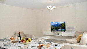 Un comedor moderno con una mesa dispuesta para el desayuno, un televisor y un sofá.