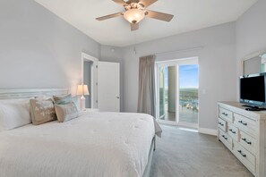 A hotel room with a bed, a television, a ceiling fan, and a view of the ocean through a sliding door. - Escape to one of the Gulf Coast's premier destinations. Turquoise Place in Orange Beach, Alabama (Orange Beach)