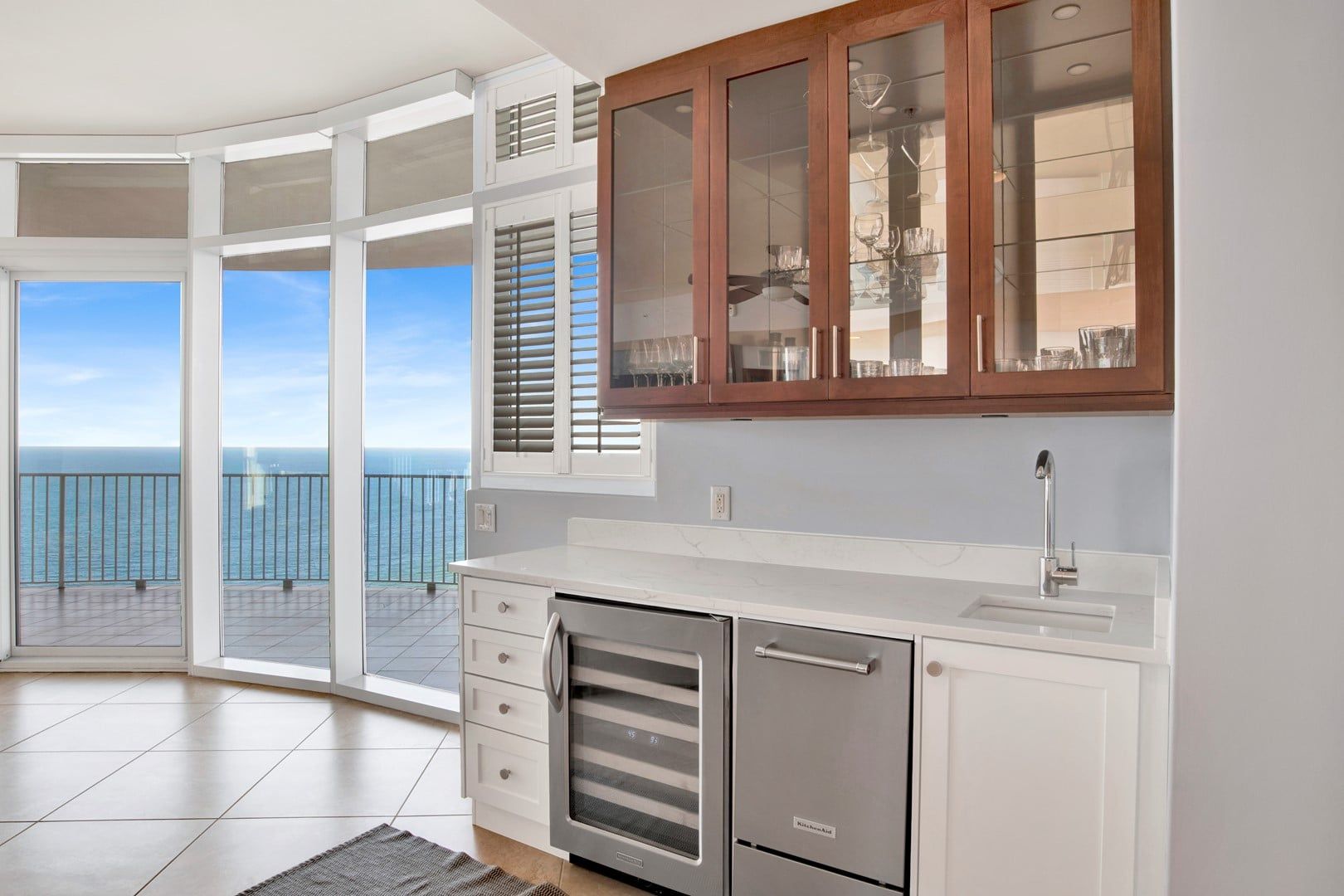 A kitchen with a view of the sea, a built-in oven, and a cabinet with glass doors.