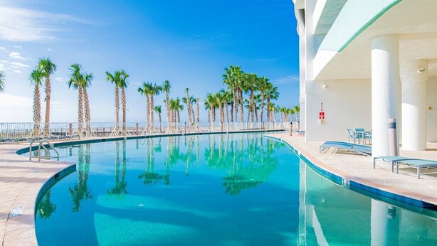 Una piscina amb palmeres i vista a l'oceà.