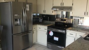 Una cocina moderna con electrodomésticos de acero inoxidable, armarios blancos y piso de baldosas.