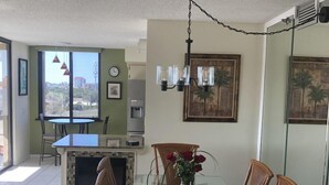 Un comedor con una mesa de vidrio y sillas de madera, una chimenea y vistas de la ciudad a través de amplios ventanales.