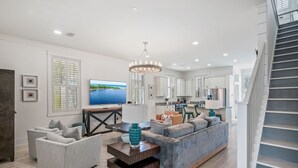 A spacious living room with a grey sofa, a blue accent piece, and a flat-screen TV. - WaterColor Escape |Bring the Whole Family—Pups Included! Sleeps 8 (Santa Rosa Beach)