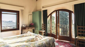 Ein Schlafzimmer mit Bett, Schreibtisch, Stuhl, Fenster und einem Balkon.