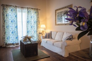 A living room with a white sofa, a wooden coffee table with a vase, a lamp, and a painting on the wall. - La Vineria (Verona)