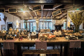 A rustic café interior with wooden tables, checkered tablecloths, hanging lights, and various food items displayed on the tables. - La Vineria (Verona)