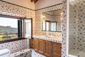 A bathroom with a large window, wooden cabinets, a sink, and a mirror. - La Vineria (Verona)